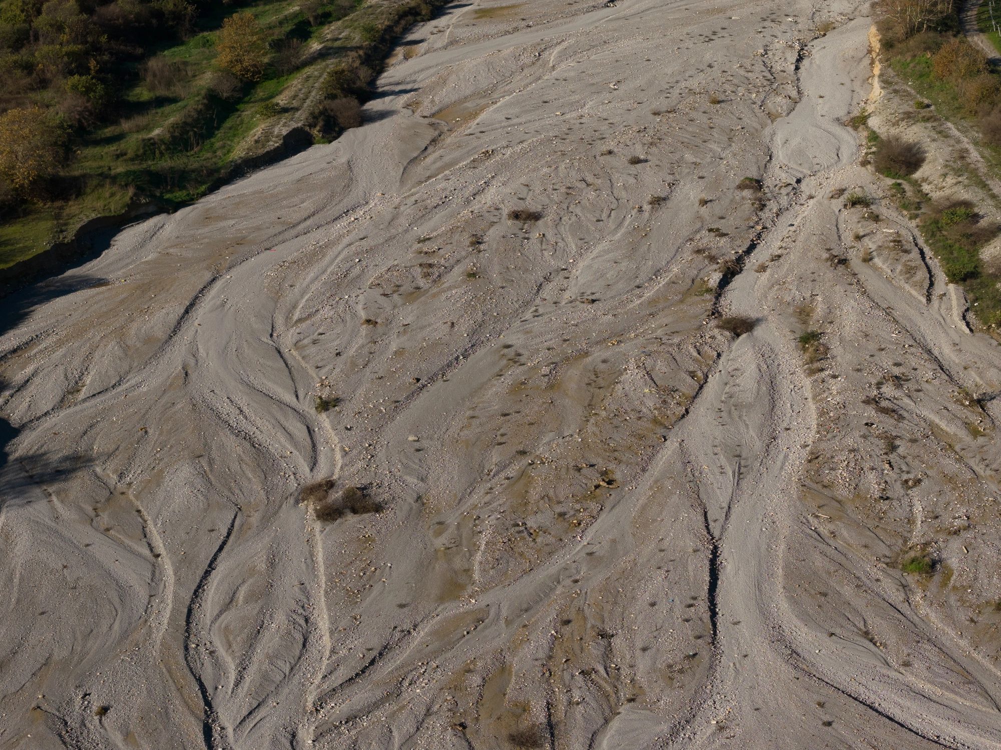 Aerial View Of Rugged Dry Riverbed With Erosion Channels And Pebble Gravel Terrain Landscape